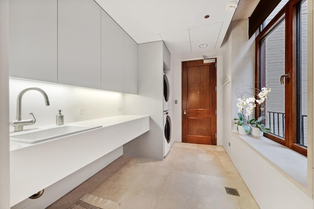 interior space featuring sink, light tile patterned floors, and stacked washer / drying machine