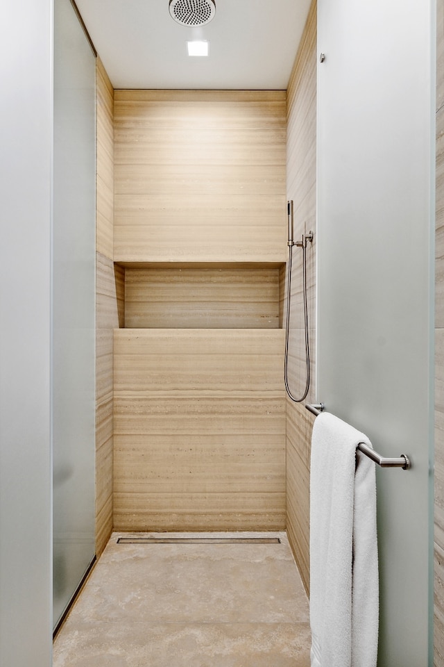 interior space with a shower, wooden walls, and concrete floors