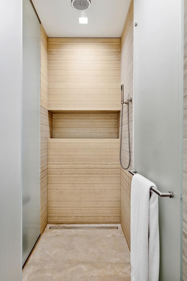 bathroom with wooden walls, a shower, and concrete floors