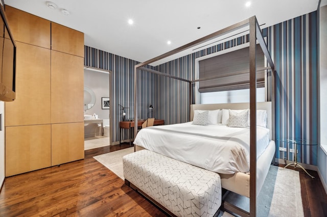 bedroom with ensuite bathroom and dark wood-type flooring