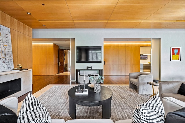 living room with hardwood / wood-style floors, wooden ceiling, a fireplace, and wooden walls