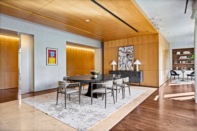 dining space featuring built in shelves, wooden ceiling, and wooden walls