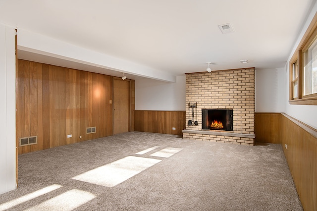 unfurnished living room with carpet, a brick fireplace, and wooden walls