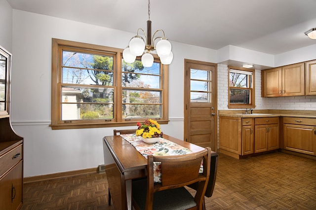 dining space featuring dark parquet floors, an inviting chandelier, and sink