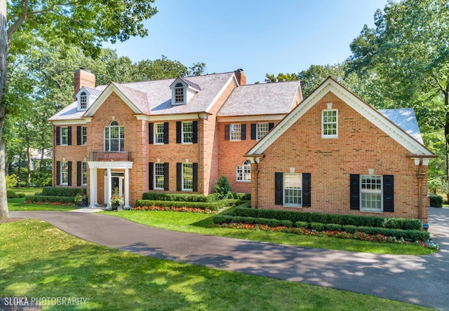 colonial inspired home with a front lawn