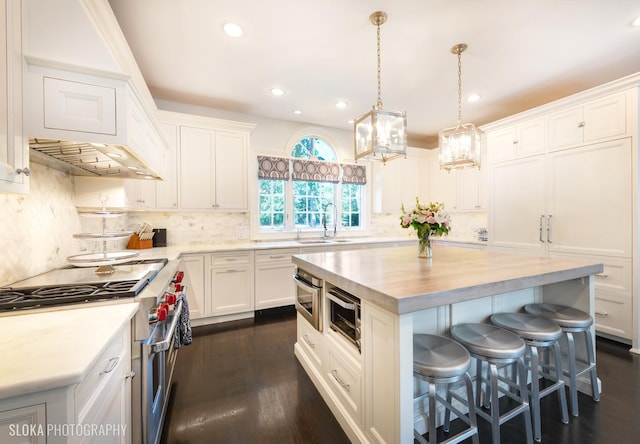 kitchen featuring built in microwave, sink, pendant lighting, white cabinets, and a center island