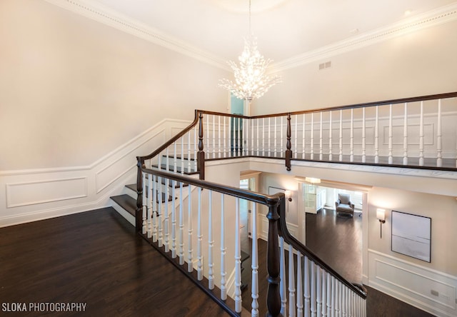 stairs with hardwood / wood-style flooring, an inviting chandelier, and ornamental molding