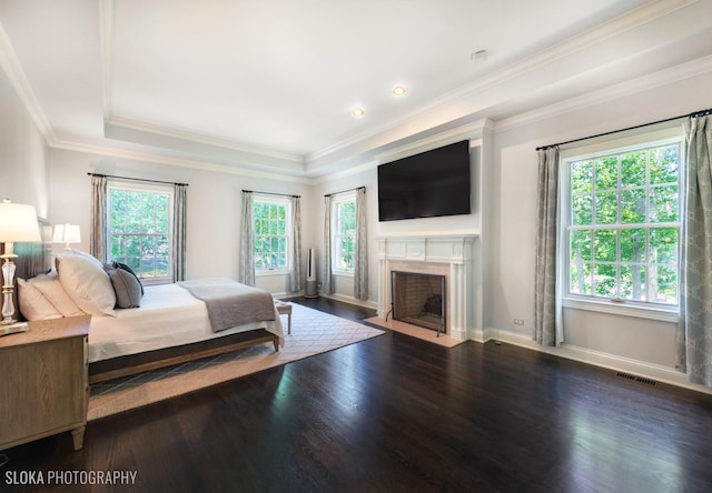 bedroom featuring dark hardwood / wood-style flooring, multiple windows, crown molding, and a tray ceiling