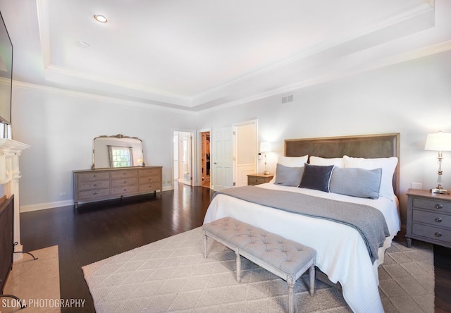 bedroom featuring dark hardwood / wood-style floors, ornamental molding, and a tray ceiling