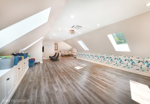 additional living space featuring vaulted ceiling with skylight and light wood-type flooring