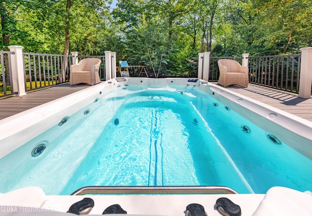 view of swimming pool featuring an outdoor hot tub and a wooden deck