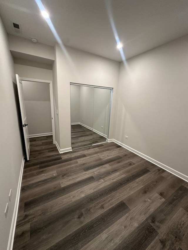 unfurnished bedroom featuring a closet and dark wood-type flooring