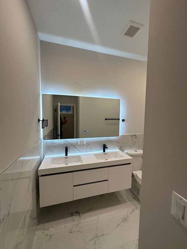 bathroom featuring vanity, toilet, and tile walls