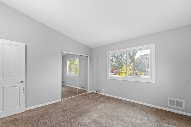 unfurnished bedroom with dark carpet, lofted ceiling, and a closet