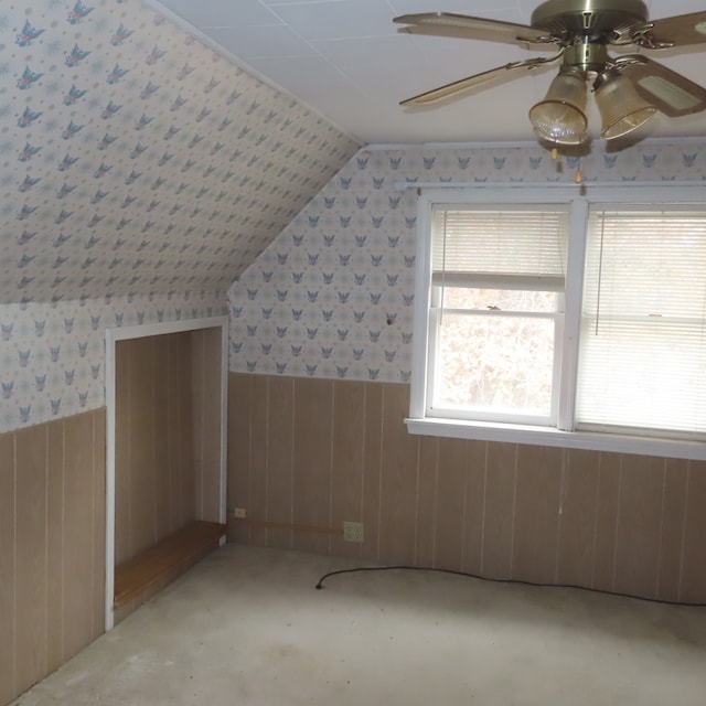 bonus room featuring ceiling fan, wooden walls, and vaulted ceiling