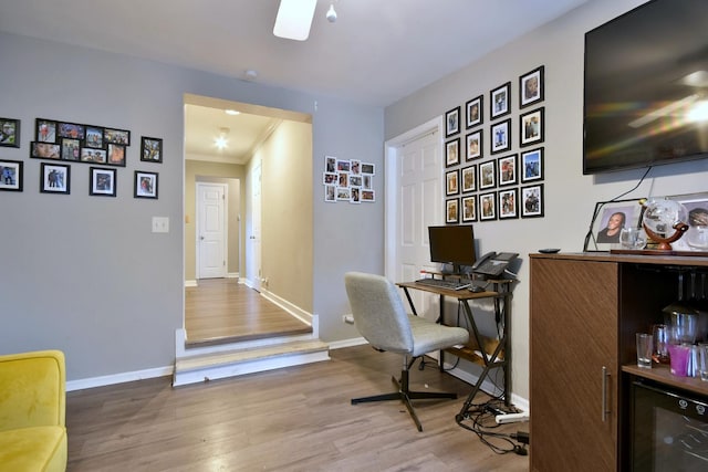 home office featuring hardwood / wood-style floors, ornamental molding, beverage cooler, and indoor bar