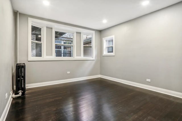 unfurnished room featuring radiator and dark hardwood / wood-style flooring