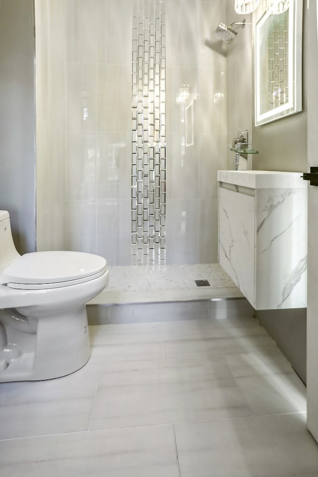 bathroom featuring tile patterned flooring, toilet, and tiled shower