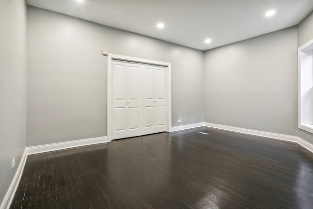 unfurnished bedroom featuring a closet and dark wood-type flooring