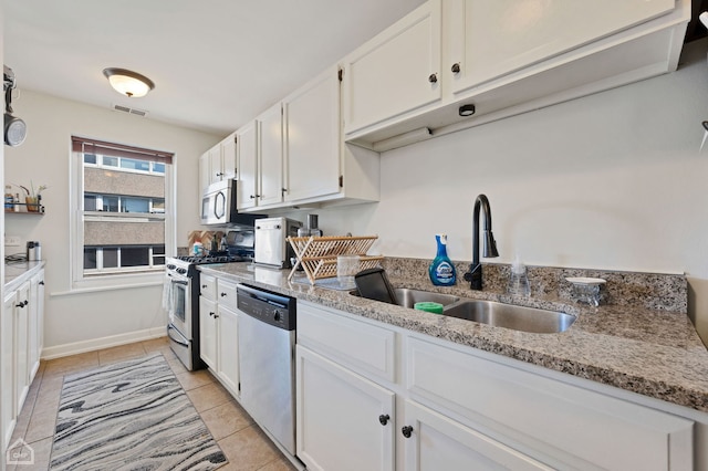 kitchen with white cabinetry, appliances with stainless steel finishes, light stone countertops, and sink