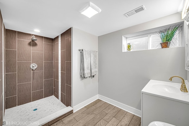 bathroom with a tile shower, hardwood / wood-style floors, and vanity