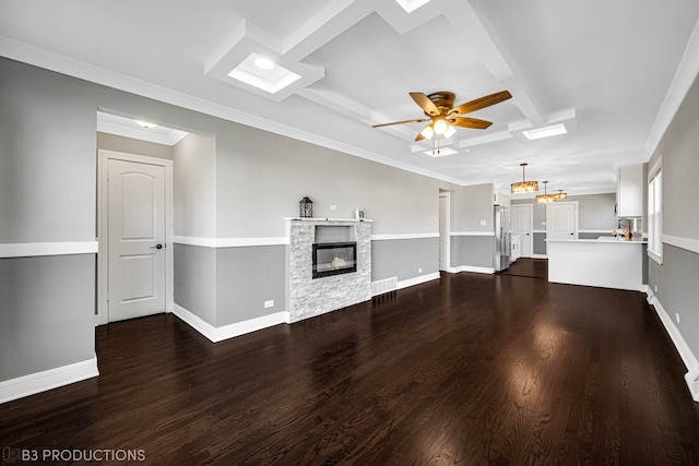 unfurnished living room with ceiling fan, ornamental molding, a fireplace, beamed ceiling, and dark hardwood / wood-style flooring