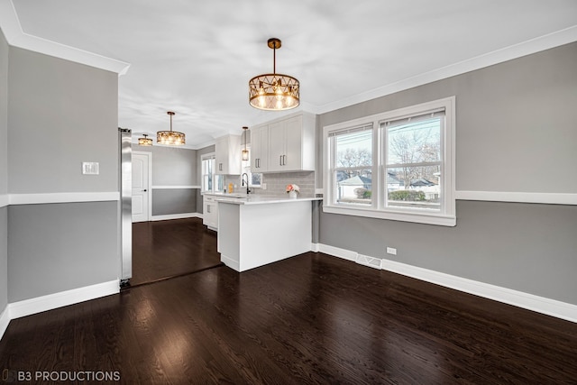 kitchen featuring white cabinetry, dark wood-type flooring, tasteful backsplash, kitchen peninsula, and decorative light fixtures