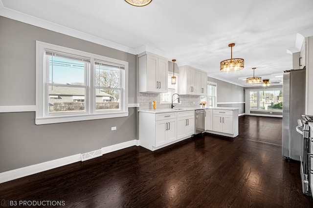 kitchen with sink, hanging light fixtures, white cabinetry, kitchen peninsula, and stainless steel appliances