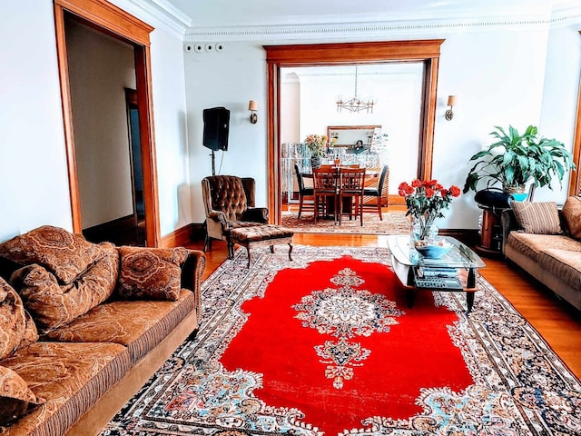 living room with wood-type flooring, a notable chandelier, and crown molding