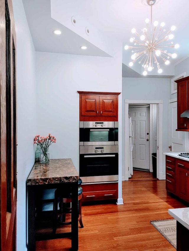 kitchen with a notable chandelier, white appliances, and light hardwood / wood-style flooring