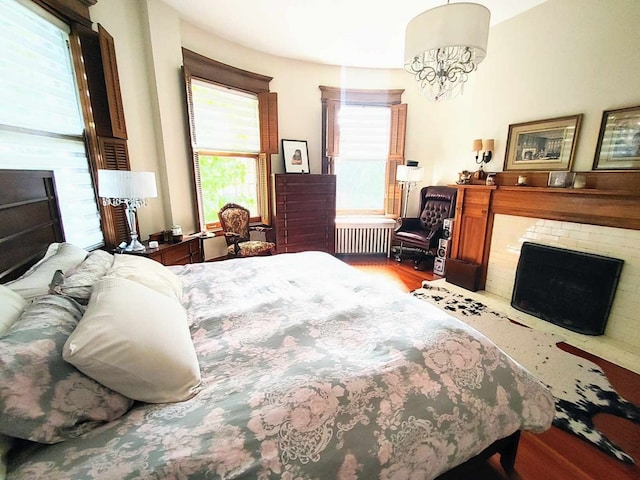 bedroom featuring hardwood / wood-style flooring, a brick fireplace, and radiator heating unit