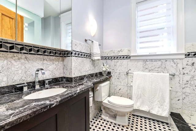 bathroom featuring vanity, tile walls, and toilet