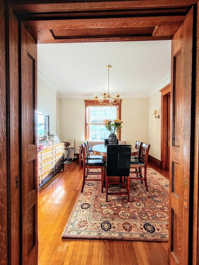 dining area with an inviting chandelier, hardwood / wood-style flooring, and ornamental molding