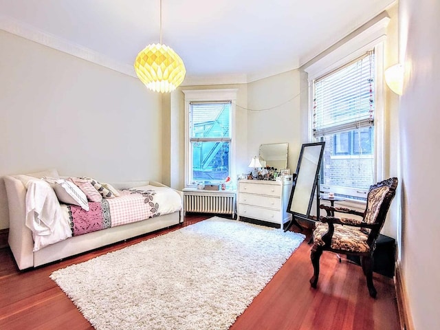 bedroom with crown molding, dark wood-type flooring, and radiator heating unit