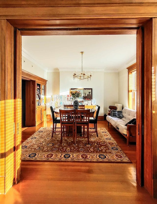 dining room featuring crown molding, wood-type flooring, and a chandelier