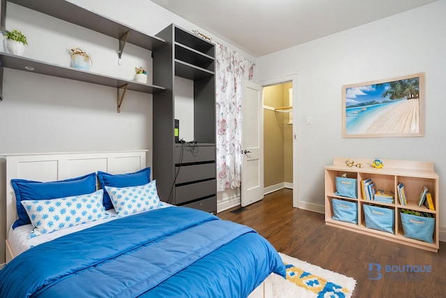 bedroom with a walk in closet, a closet, and dark hardwood / wood-style floors