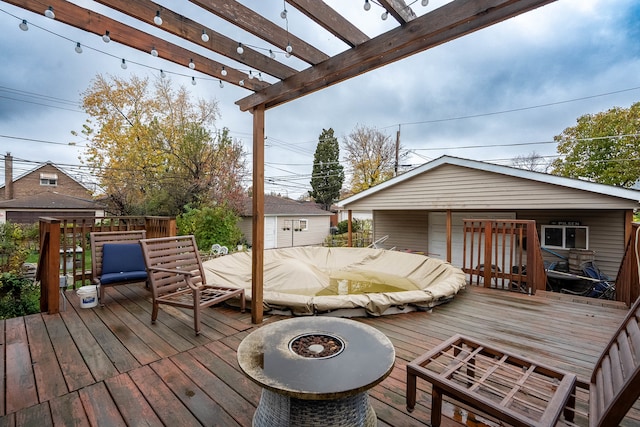 wooden deck with a fire pit, an outdoor structure, and a pergola