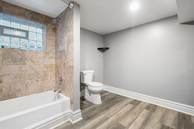 bathroom featuring tiled shower / bath combo, toilet, and wood-type flooring