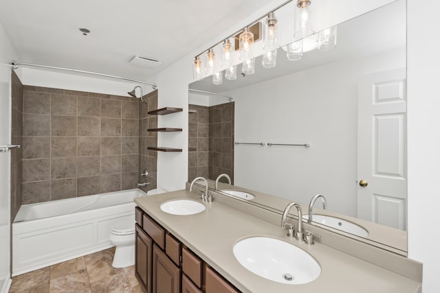 full bathroom featuring vanity, tiled shower / bath, and toilet