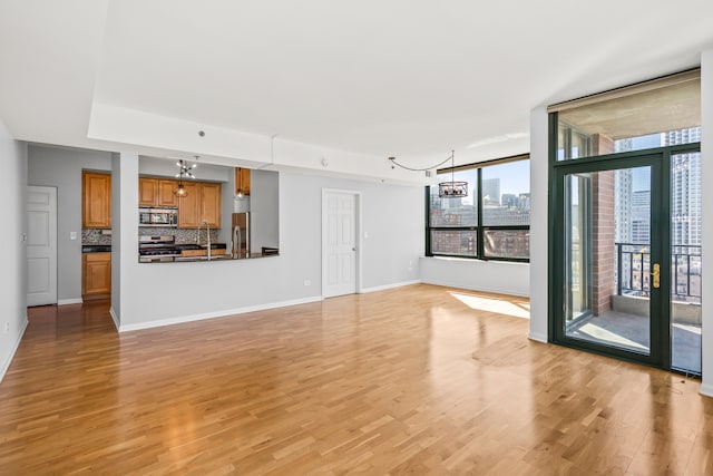 unfurnished living room with floor to ceiling windows, light hardwood / wood-style flooring, and a notable chandelier