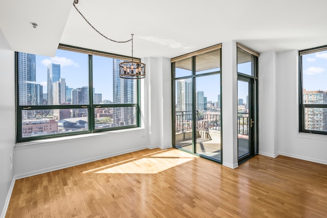 empty room with wood-type flooring, a wall of windows, and a notable chandelier