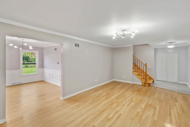 spare room featuring light hardwood / wood-style floors, crown molding, and an inviting chandelier