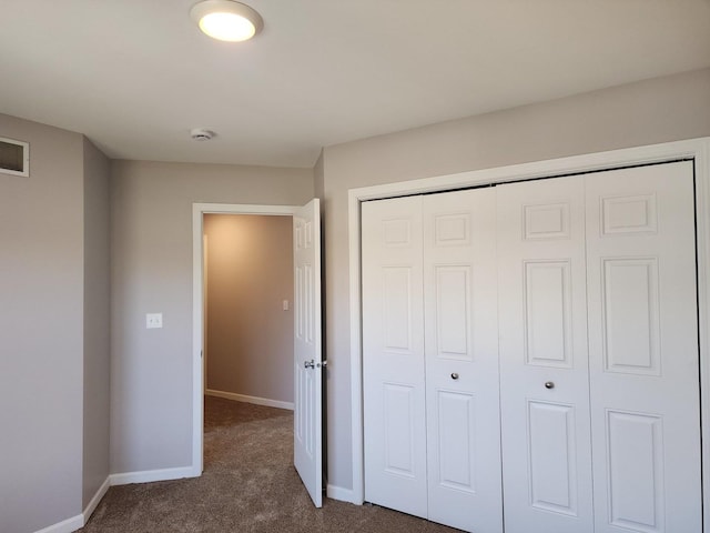 unfurnished bedroom with a closet and dark carpet