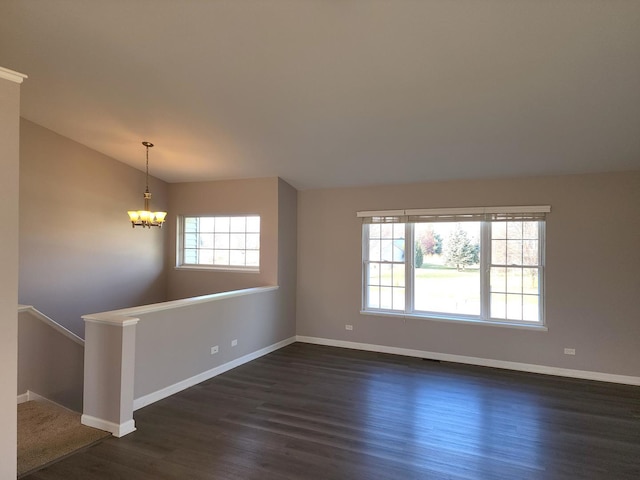 spare room with a notable chandelier, dark hardwood / wood-style flooring, and vaulted ceiling