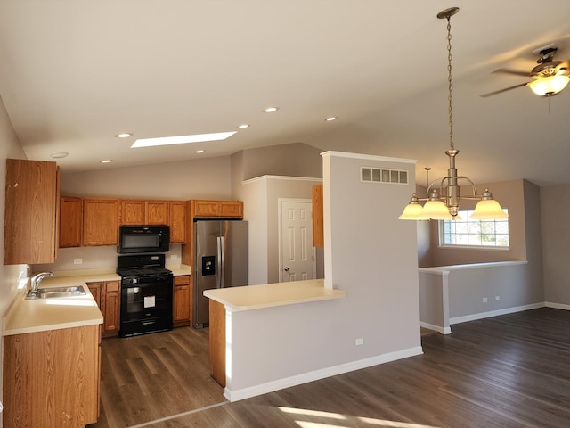 kitchen with vaulted ceiling with skylight, sink, black appliances, dark hardwood / wood-style floors, and hanging light fixtures