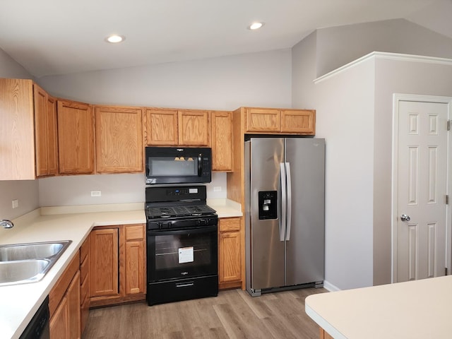 kitchen featuring sink, black appliances, lofted ceiling, and light hardwood / wood-style flooring