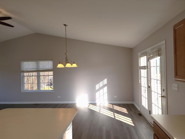 unfurnished dining area with dark hardwood / wood-style floors, ceiling fan with notable chandelier, and vaulted ceiling