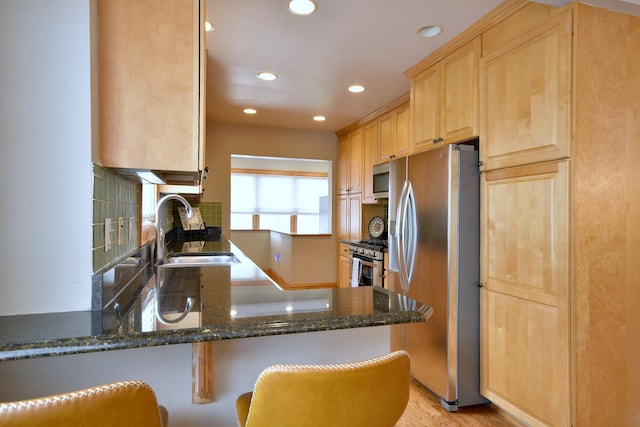 kitchen featuring dark stone counters, kitchen peninsula, sink, and stainless steel appliances