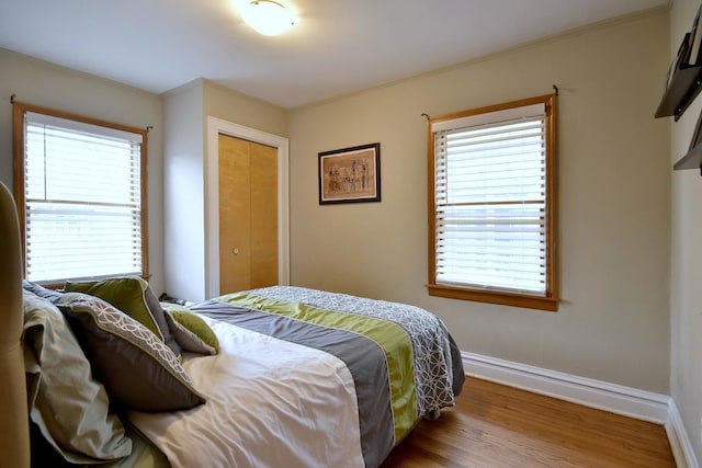 bedroom with hardwood / wood-style floors, a closet, and crown molding