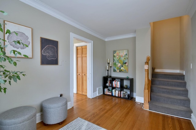 living area with wood-type flooring and ornamental molding